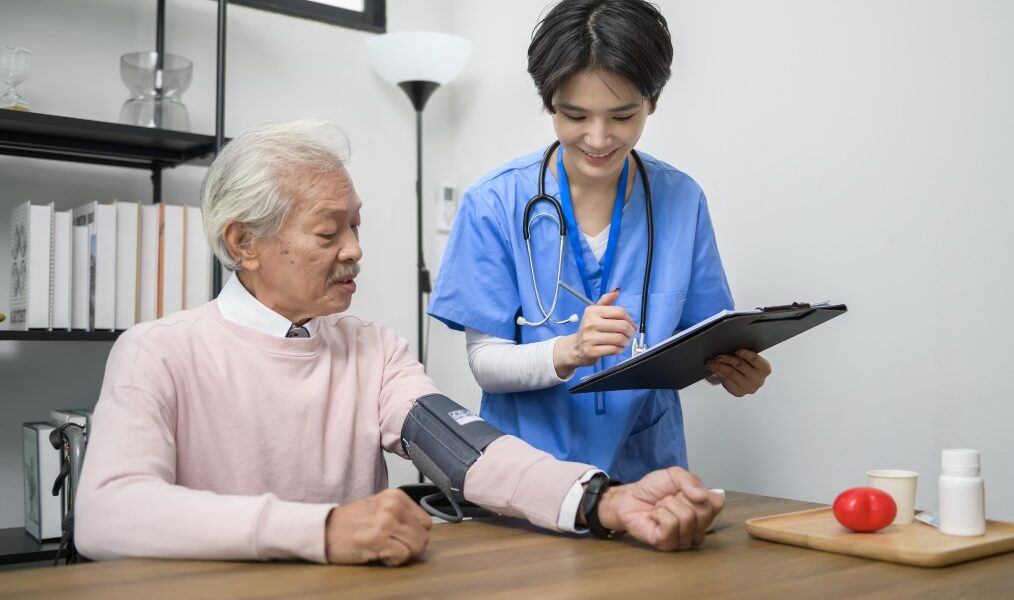 Infirmière en EHPAD prenant la tension d’un résident pour le suivi médical dans un logiciel de soins