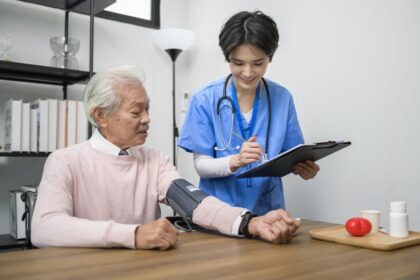 Infirmière en EHPAD prenant la tension d’un résident pour le suivi médical dans un logiciel de soins