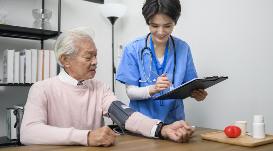 Infirmière en EHPAD prenant la tension d’un résident pour le suivi médical dans un logiciel de soins