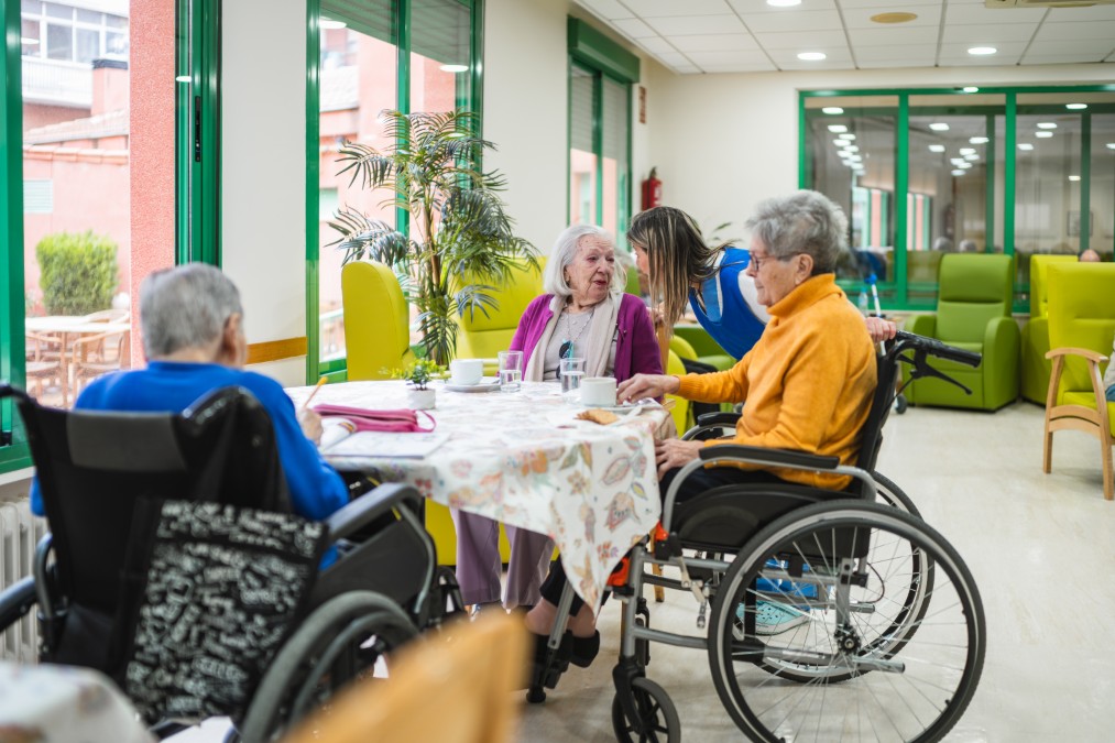 Résidents d’un EHPAD discutant avec une soignante dans un espace de vie
